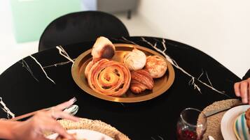 A round table with a black marble top, a plate of pastries, and a glass of red drink.