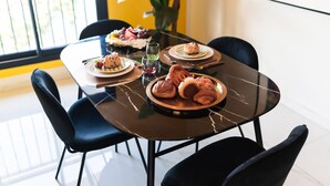 Une table à manger avec des assiettes remplies de nourriture, un verre de vin et des chaises noires.