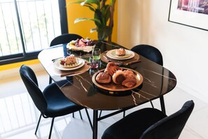 Una mesa de comedor con platos de comida, una copa de vino y sillas negras.