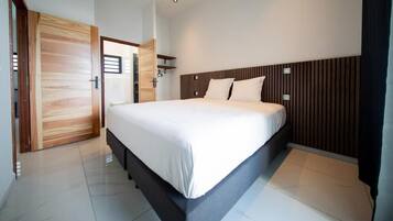 A modern bedroom with a large bed, wooden paneling on the headboard, and a bright, clean design.