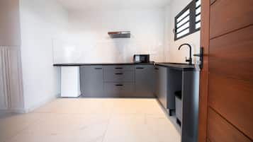 Een moderne keuken met een zwart aanrecht, witte tegels en een houten deur.
