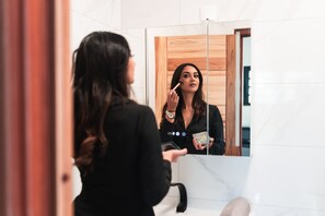 A person in a bathroom with a mirror, a sink, and a wooden door.