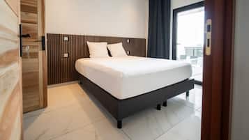 Une chambre d’hôtel moderne dotée d’un grand lit, d’une tête de lit en bois et offrant une vue sur la ville grâce à une grande fenêtre.