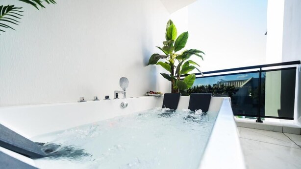 A modern indoor hot tub with a clear view of the sky and a large plant beside it. - Takeoff (SAINTE-MARIE)