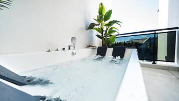 A modern indoor hot tub with a clear view of the sky and a large plant beside it.