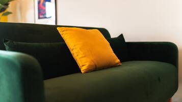 A green sofa with a single yellow pillow.