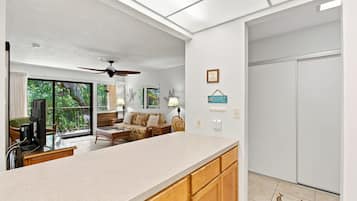 A spacious living area with a large window, a ceiling fan, a sofa, and a dining table.