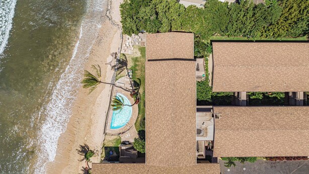 Vista aérea de una propiedad costera con piscina, acceso a la playa y varias edificaciones de techos planos.