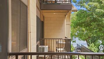 A balcony with a view of a body of water, a small outdoor seating area, and a building with a brick facade.