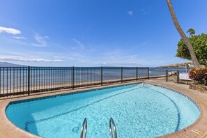 En swimmingpool med utsikt över havet och ett staket.