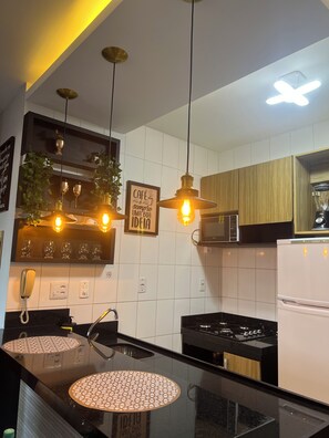 A modern kitchen with a central island, built-in appliances, and pendant lighting. - 1303  Nobre e Moderno com Garagem (Belém)