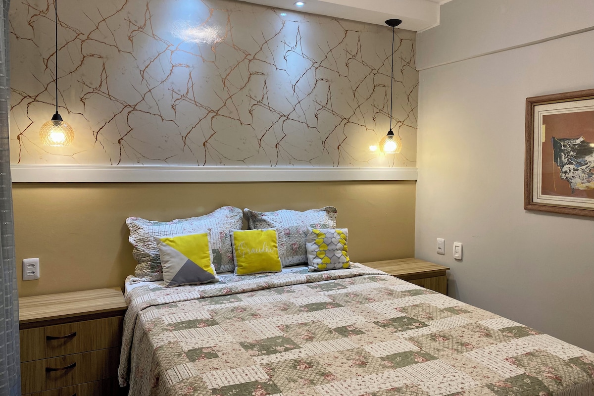 A bedroom with a bed, bedside tables, a wall with a crackled pattern, and pendant lights.