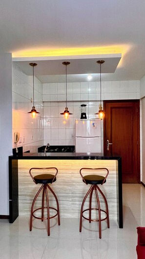 A modern kitchen with a central island, pendant lighting, and two bar stools. - 1303  Nobre e Moderno com Garagem (Belém)