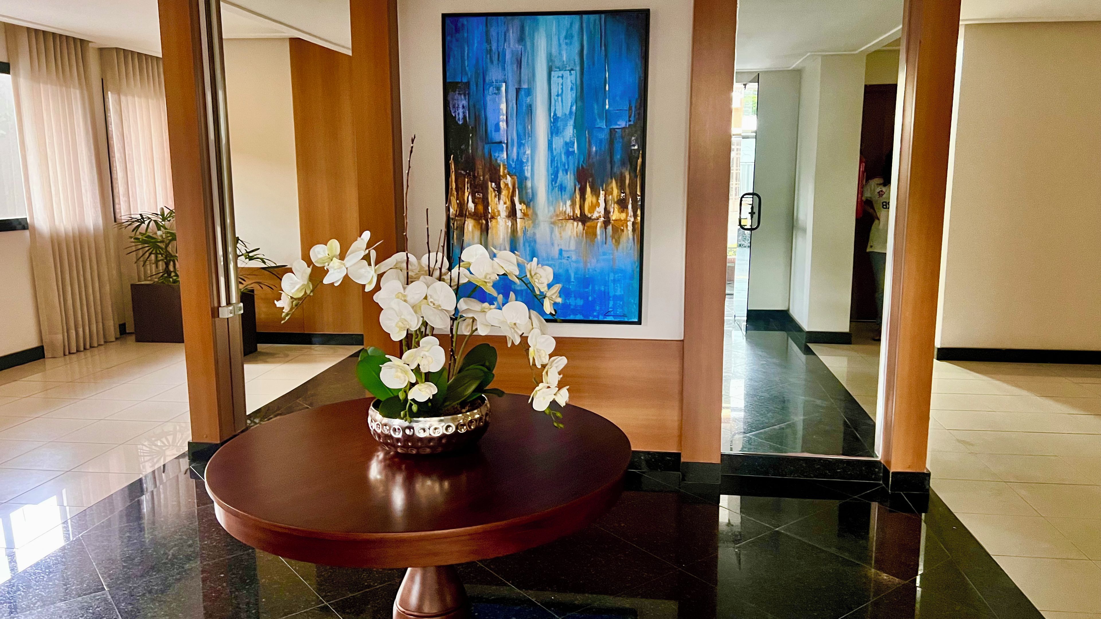 Um hall com uma mesa redonda, uma pintura e um vaso de planta.