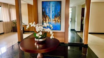 Um hall com uma mesa redonda, uma pintura e um vaso de planta.