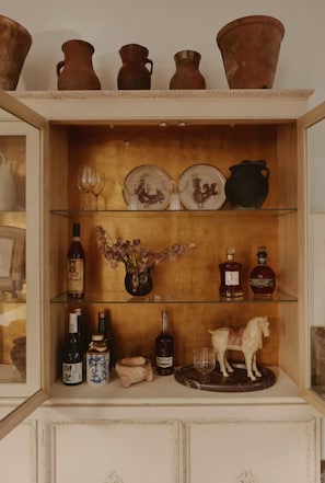 A wooden cabinet with shelves containing pottery, glassware, and bottles. - Mediterranean Retreat. Newly renovate 1,000 sqft. (Chicago)