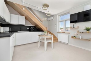 A modern kitchen with white cabinets, a black countertop, and a wooden staircase. - Spacious 2-Bedroom Apartment | Air-conditioning | City Centre (Lublin)
