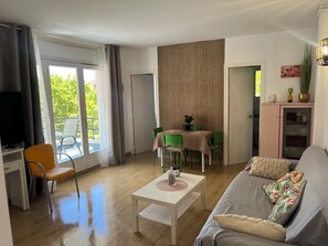 A living room with a sofa, a coffee table, a dining table with chairs, a TV, and a sliding door leading to a balcony. - Golden Aventura Salou (Salou)