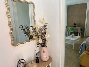 A room with a mirror, a vase with flowers, a small table, and a dining area in the background. - Golden Aventura Salou (Salou)