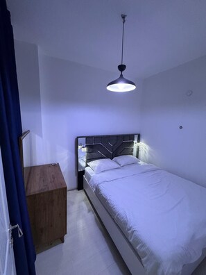 A bedroom with a bed, a bedside table, and a hanging light fixture. - amur (istanbul)