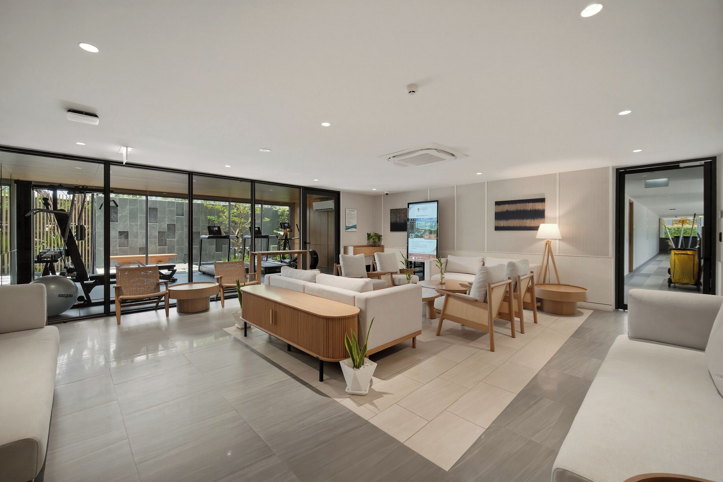 A spacious living area with a large window, a sofa set, a coffee table, and exercise equipment.