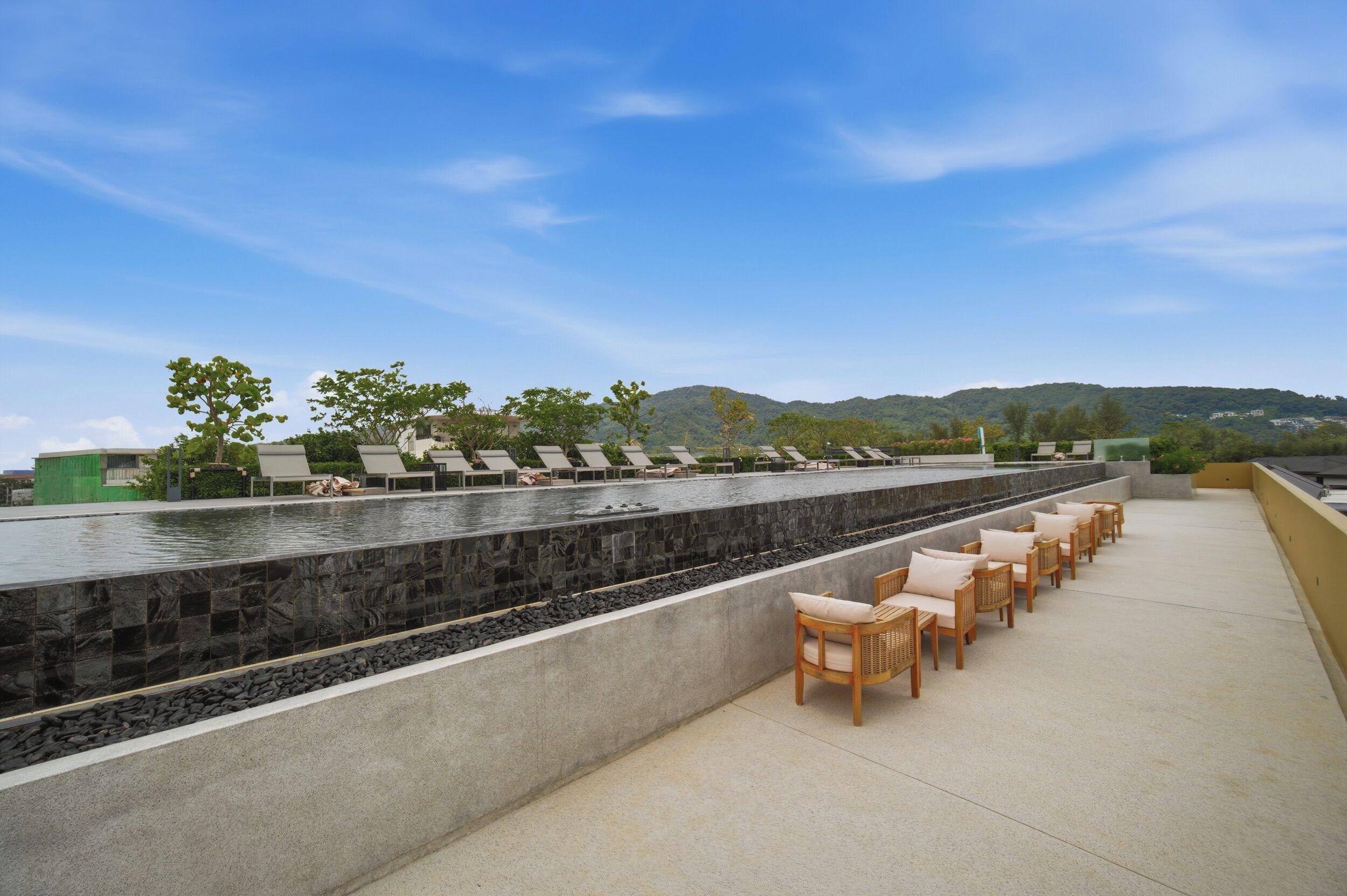 A rooftop terrace with a pool, lounge chairs, and a view of the mountains.