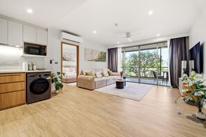 A modern apartment with a kitchen, a living area with a sofa and coffee table, a dining area, and a balcony with a view. - Seashore Beach Residences by NLA (Choeng Thale)