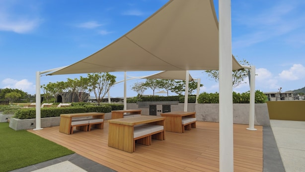 An outdoor patio with wooden furniture and a large canopy. - Seashore Beach Residences by NLA (Choeng Thale)