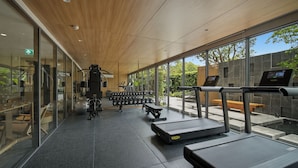 A modern gym with exercise equipment, a treadmill, and a bench. - Seashore Beach Residences by NLA (Choeng Thale)
