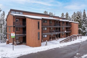 A multi-story wooden building with balconies, a snow-covered ground, and a clear sky. - Beaver Village Unit 624 2 bed remodeled, private deck w/forest views (Winter Park)