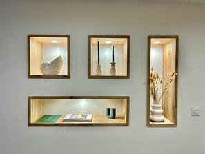 Three framed artworks on a wall, each with a different design, and a lower shelf with a book and a vase. - The Refuge of the Six Valleys • House for 8 people, 4 bedrooms  • Wi-Fi• Near the Alps (Livet-et-Gavet)