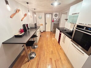 A modern kitchen with a black countertop, stainless steel appliances, and wooden flooring. - The Refuge of the Six Valleys • House for 8 people, 4 bedrooms  • Wi-Fi• Near the Alps (Livet-et-Gavet)