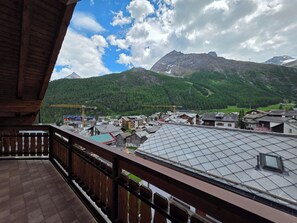 En balkong med utsikt över ett bergskedja, en by och en byggkran.
