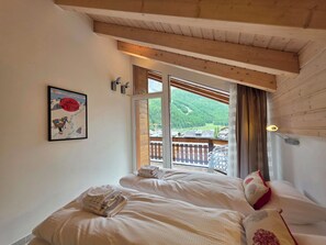 Ein Schlafzimmer mit einem Bett, einem Fenster mit Bergblick und einem Bild an der Wand.