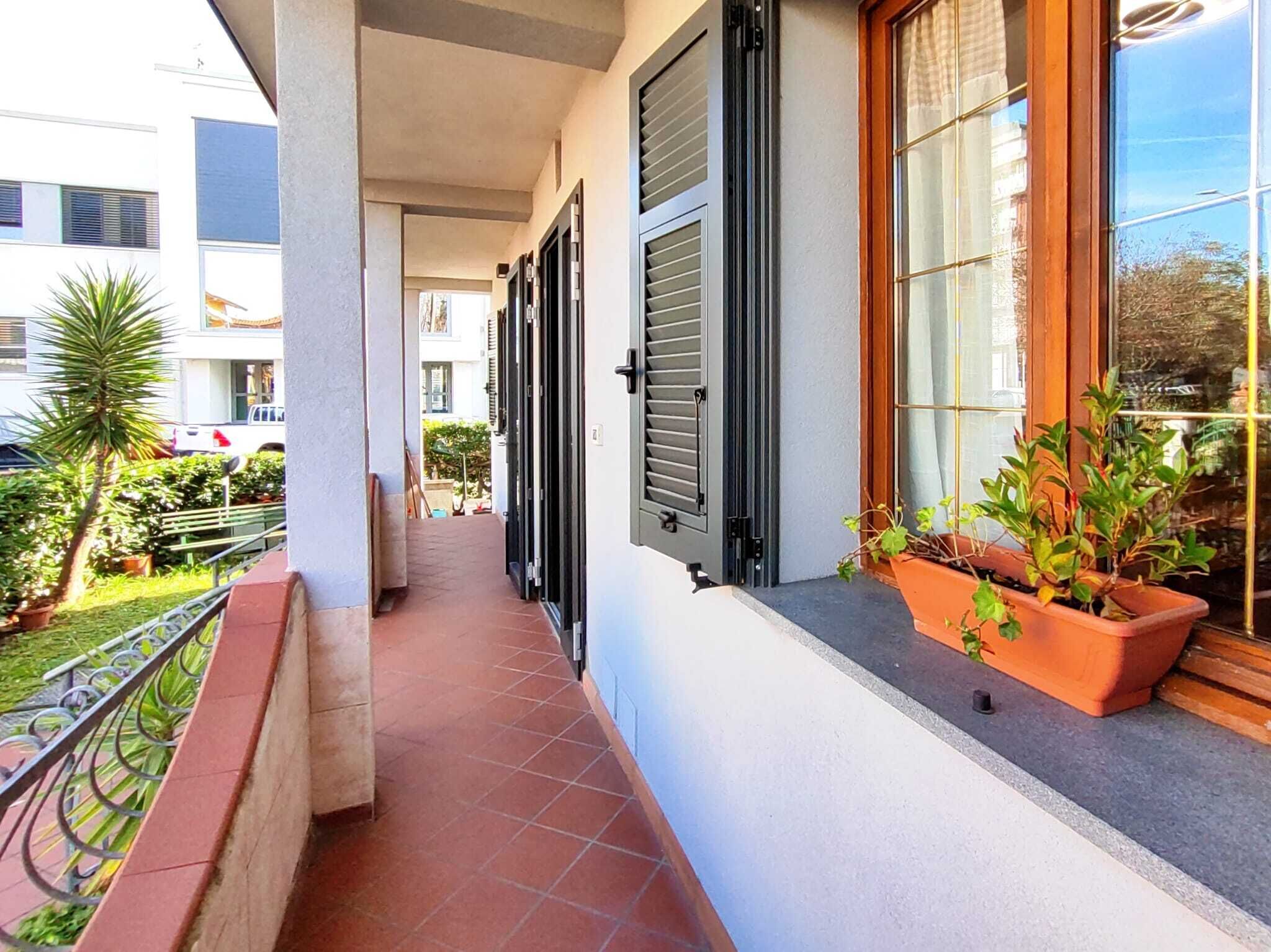 Un balcone stretto con pavimento piastrellato, ringhiera in metallo e piante in vaso.
