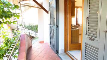 A balcony with a tiled floor, a metal railing, and a view of a residential area.