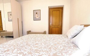 Ein Schlafzimmer mit Bett, Stuhl, Kleiderschrank und einer Tür.