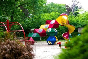 Ein Spielplatz mit einer roten Rutsche und einer Kletteranlage.