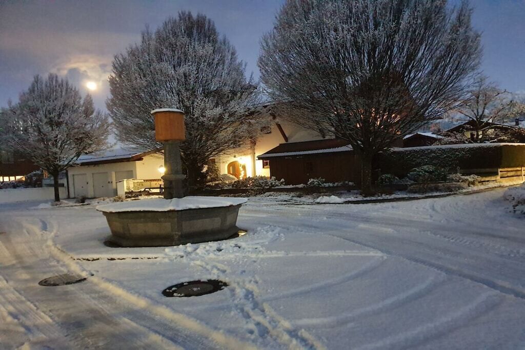 A snow-covered landscape with a building featuring a large chimney and a snow-covered roof.