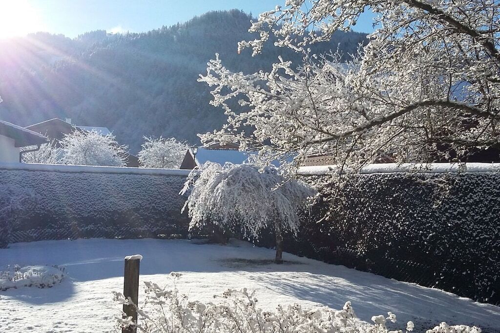 Paisagem coberta de neve com uma casa e árvores.