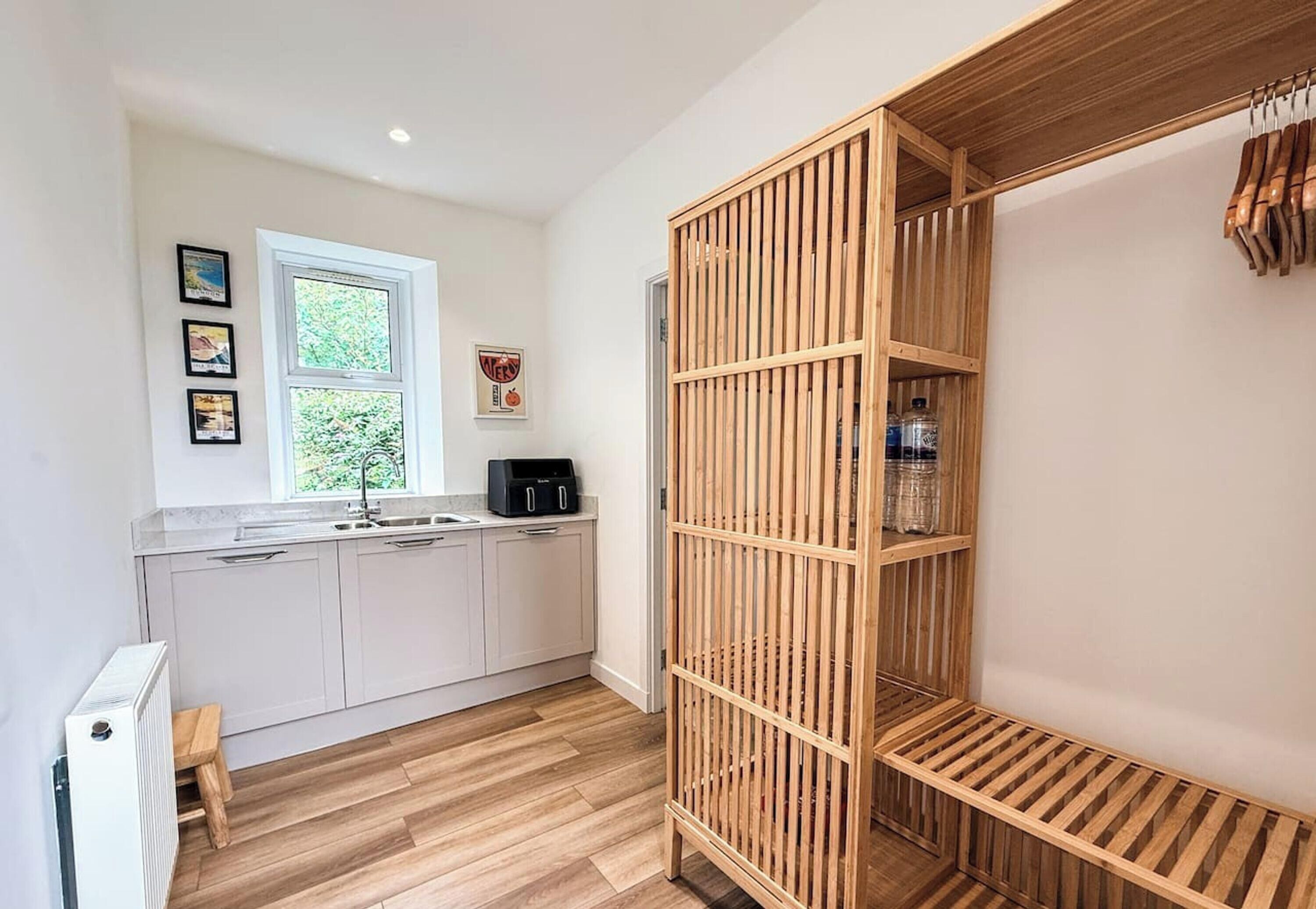 A modern kitchen with a window, wooden shelving, and a radiator.