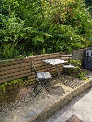 Een houten bank en een metalen tafel met stoelen in een tuin.