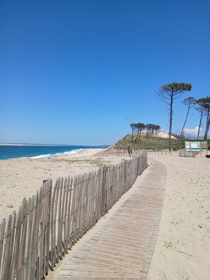 A wooden boardwalk along a sandy beach with a clear blue sky. - 3-Person "Gite Étoiles" (BISCARROSSE PLAGE)