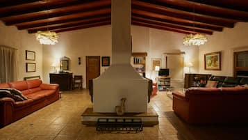 A cozy living room with a fireplace, red sofas, and a tiled floor.
