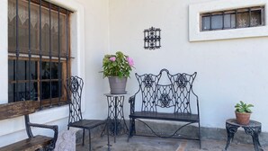 Une cour avec un banc, une petite table et un pot de fleurs.