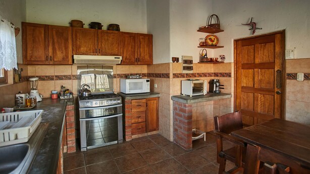 Une cuisine avec des meubles de rangement en bois, une cuisinière à gaz, un four à micro-ondes et un grille-pain.
