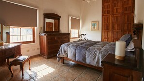 Une chambre à coucher comprenant un lit, une armoire en bois, une commode et un bureau avec une chaise.