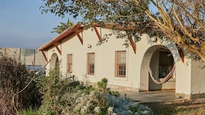 A building with a white facade, multiple windows, and a hammock in the yard. - w Nature Retreat 4BR w Pool BBQ in Ca ete (Quilmaná)
