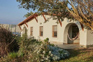 A building with a white facade, multiple windows, and a hammock in the yard. - w Nature Retreat 4BR w Pool BBQ in Ca ete (Quilmaná)