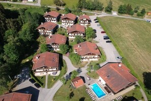 A residential area with multiple houses, a swimming pool, and a parking lot. - Panorama with indoor swimming pool (Hauzenberg)
